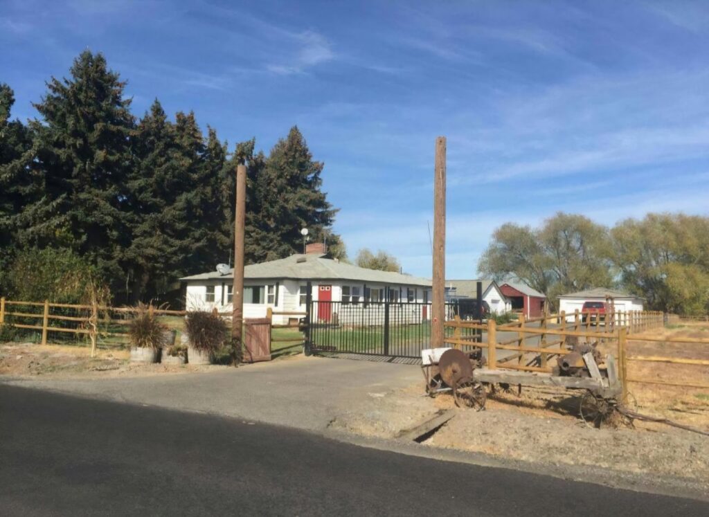 A property entrance featuring a black metal gate and wooden rail fencing by Integrity Gates and Fencing in Yakima, WA