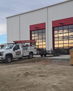 Prutch's Garage Door service truck with a trailer parked at a commercial garage door installation site in Colorado Springs, CO
