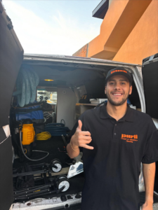 A Purli technician smiling in front of a service van with carpet cleaning equipment in San Diego, CA.