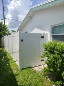 A durable white PVC privacy fence with a gate installed alongside a residential property by MY PVC Fences in Miami, FL.
