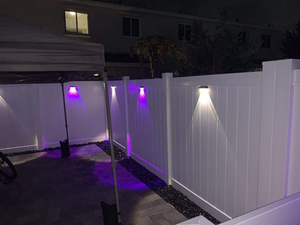 A modern white PVC privacy fence illuminated with stylish purple accent lighting by MY PVC Fences in Miami, FL.