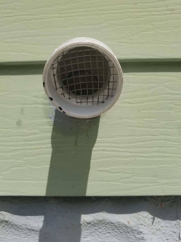 A PVC vent pipe with a protective screen installed on the exterior of a home by A-OK Heating & Cooling in Concord, GA.