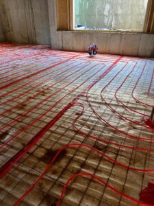 Red radiant floor heating pipes being installed during a construction project by Alan Energy Services in Naperville, IL