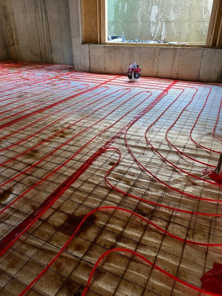 Red radiant floor heating pipes being installed during a construction project by Alan Energy Services in Naperville, IL