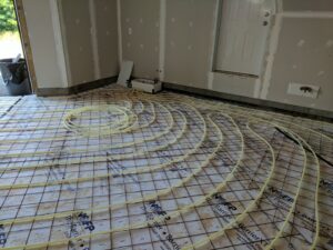 Radiant floor heating tubes laid out on a subfloor during installation by Huether Heating & Cooling Inc in Rochester, NY.