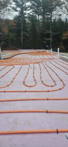 Radiant floor heating tubes being installed on a concrete slab by Ultra Installs in Barrington, NH