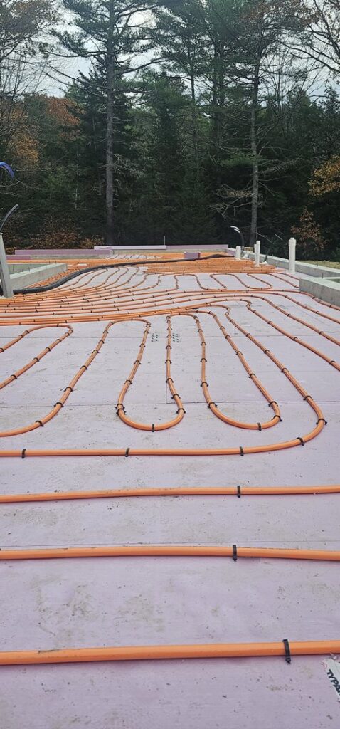 Radiant floor heating tubes being installed on a concrete slab by Ultra Installs in Barrington, NH