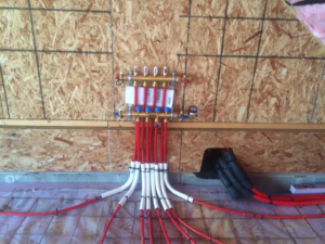 Close-up of a radiant floor heating manifold with PEX tubing connections installed by Gil-Rich Cooling & Heating LLC in Flint, MI