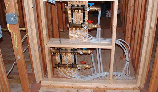 Radiant floor heating manifolds and piping installed within wall studs by Pugh Heating & Air Conditioning in Holland, OH.