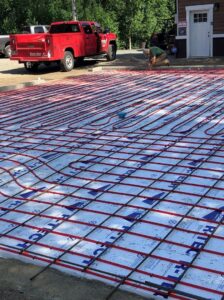 Radiant floor heating tubing laid out on insulation and rebar during installation by Boiler Man Plumbing & Heating in Palmer, AK