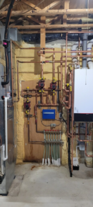 A detailed view of a radiant heating manifold and copper piping installed by Crome Mechanical Inc. in Cedar Springs, MI
