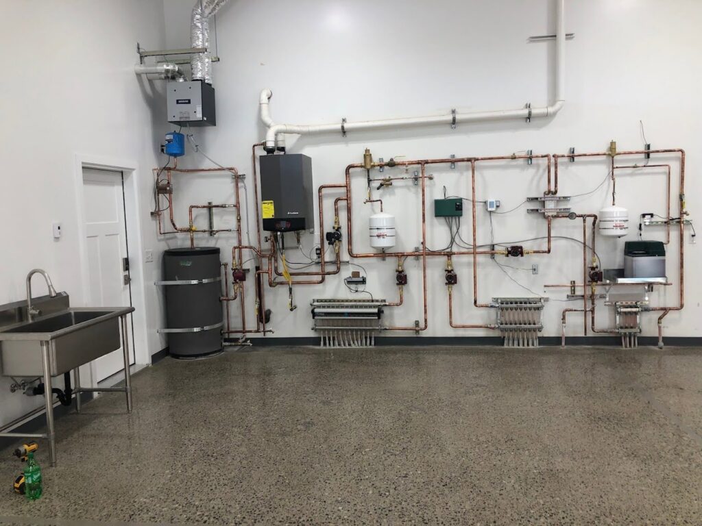 A comprehensive radiant heating system with boiler, water heater, and manifolds by Boiler Man Plumbing & Heating in Palmer, AK