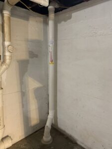 An interior view of a radon mitigation pipe installed in a basement by Protect Environmental in Louisville, KY