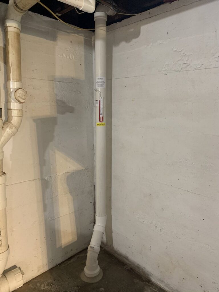 An interior view of a radon mitigation pipe installed in a basement by Protect Environmental in Louisville, KY