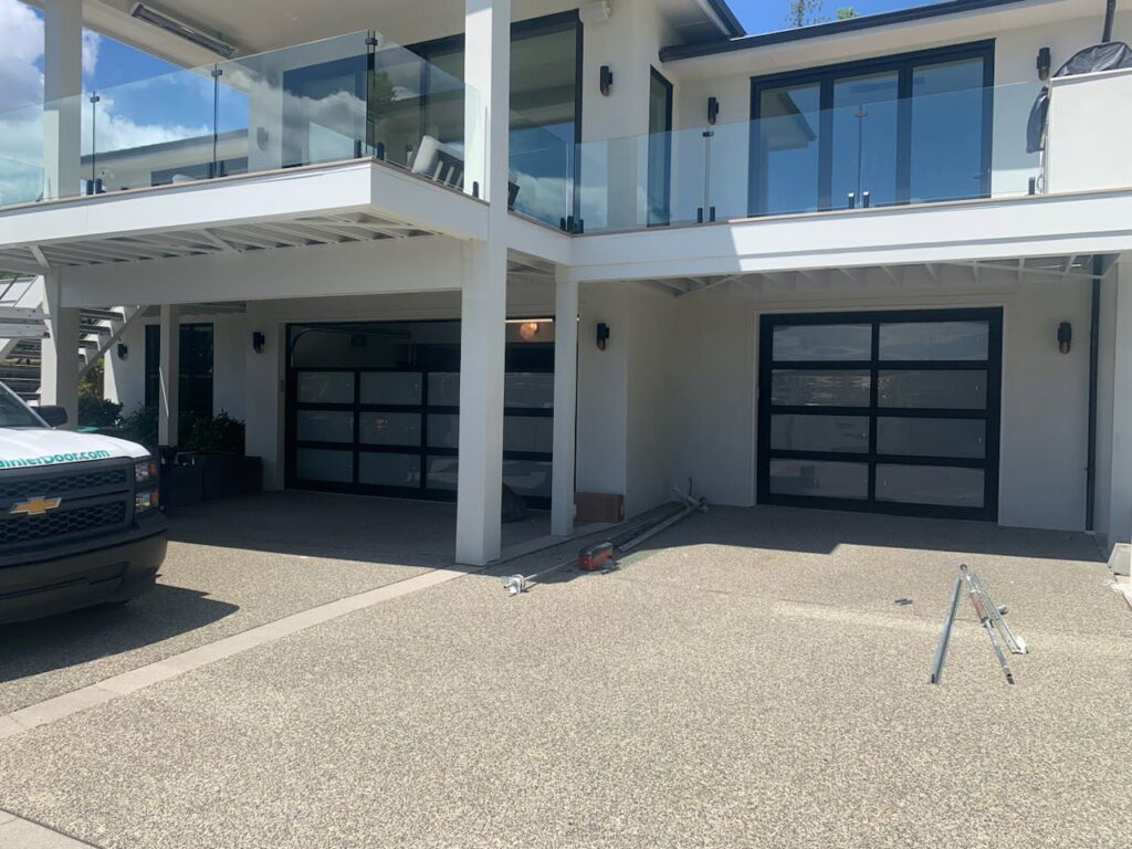 A Rainier Garage Door service truck and tools at a job site with two modern garage doors in Bellevue, WA.