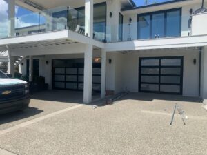 A Rainier Garage Door service truck and tools at a job site with two modern garage doors in Bellevue, WA.