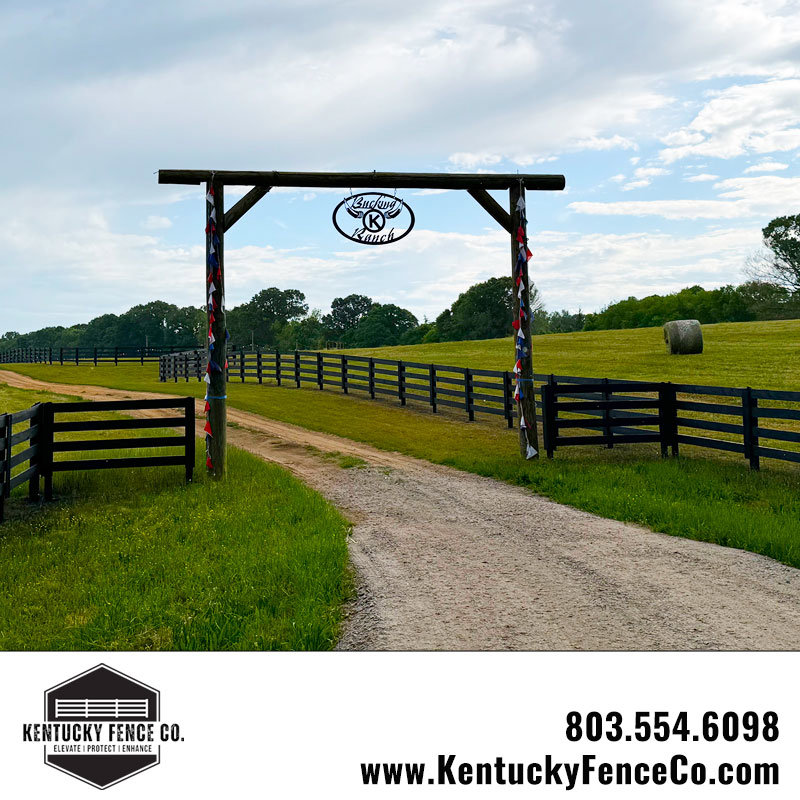 A ranch entrance featuring a wooden archway and black wood fences installed by Kentucky Fence Co in McConnells, SC.