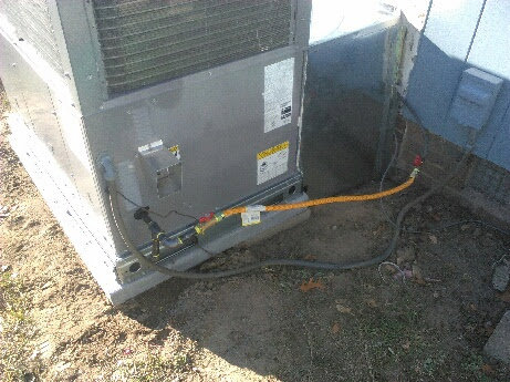 Rear view of an outdoor HVAC unit showing refrigerant lines and electrical connections by NAS Heating & Air in Fayetteville, NC.