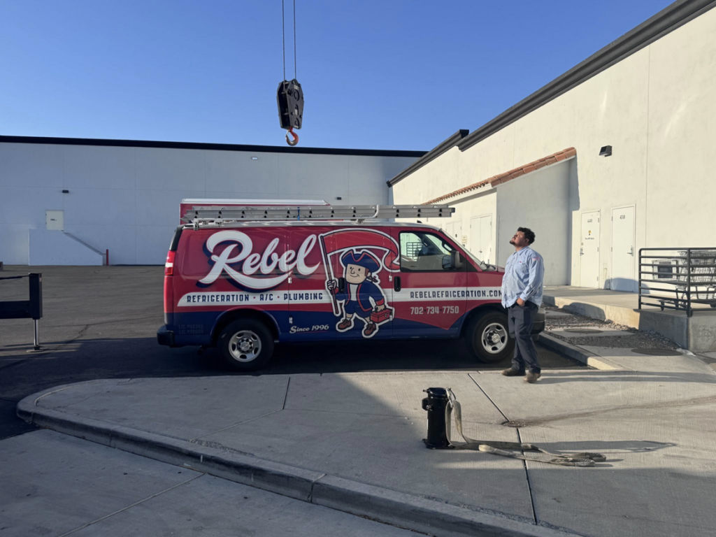 A Rebel Refrigeration van and worker on site for an HVAC installation with a crane in Las Vegas, NV.