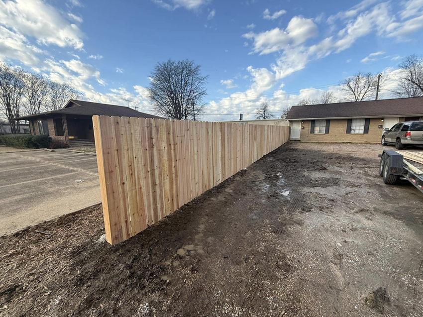 A recently installed wood fence line by Swanson Fencing in Jonesboro, AR, providing privacy for a property.
