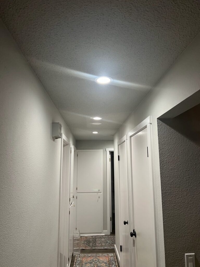 Multiple recessed lights installed and illuminated in a hallway ceiling by Andrew's Electric in Kent, WA