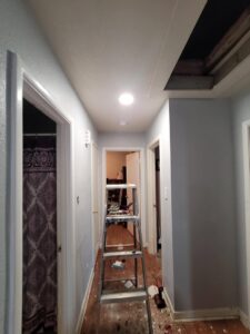 Recessed lighting installation in a hallway with a ladder, showing electrical work by Quistian Lighting in Arlington, TX