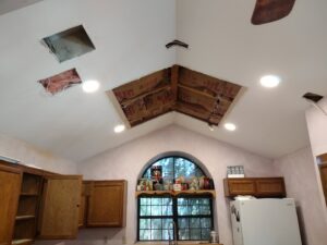 Electrician installing recessed lighting in a kitchen ceiling, showing insulation and wiring, by A Helping Hand Handyman Services in Chicago, IL.