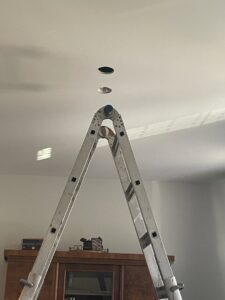 A ladder positioned for recessed lighting installation by Square Electrical LLC in Alexandria, VA, showing holes in the ceiling.