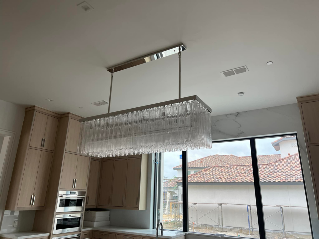 A rectangular crystal chandelier installed in a modern kitchen by Focal Electric Company in Dallas, TX.