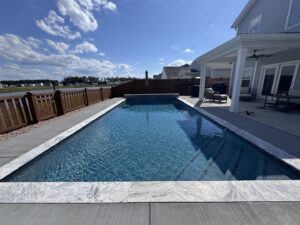 A long rectangular lap pool with a view of the waterfront, part of a backyard transformation by Salty Reef Pools LLC in Summerville, SC.