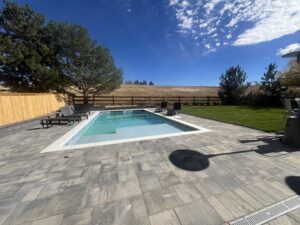 A newly installed rectangular pool with a modern paver patio by Wetworks Pool and Spa in Englewood, CO.