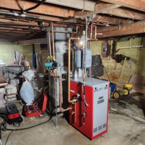 A red boiler unit with extensive copper piping installed by All The Way Heating & Cooling in Middleburgh, NY