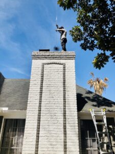 A newly installed black metal chimney cap on a red brick chimney by Brushers Chimneys in Houston, TX.