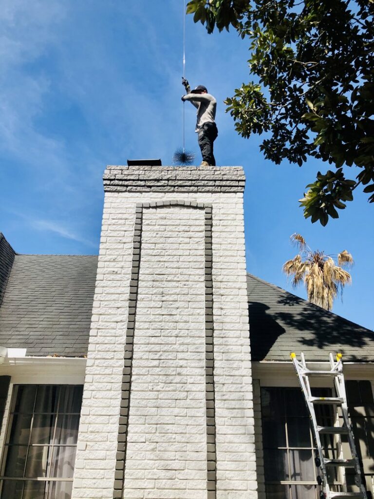 A newly installed black metal chimney cap on a red brick chimney by Brushers Chimneys in Houston, TX.