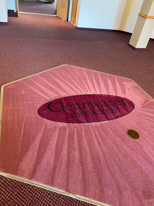 A large red carpet area with a custom 'Clearwater Estates' logo mat, demonstrating carpet services by Agwa's carpet core in Minneapolis, MN.