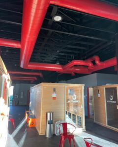 Red exposed commercial ductwork installation in a facility by Big Leaf Mechanical LLC, an HVAC contractor in South Salt Lake, UT.
