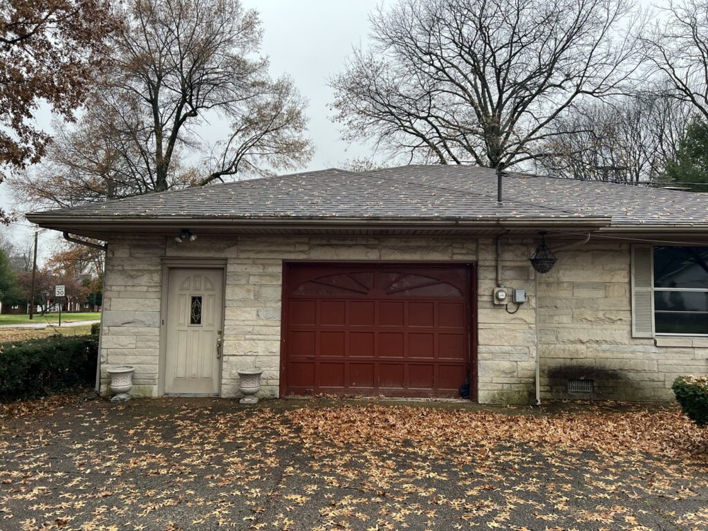 A red garage door installed on a stone house by Precision Garage Door of Owensboro Evansville in Owensboro, KY.