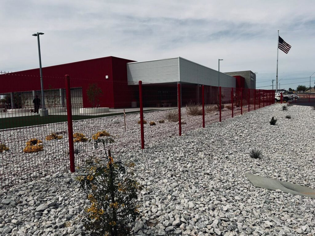 A modern red mesh security fence installed around a commercial building by SFA Contracting LLC in Tucson, AZ.