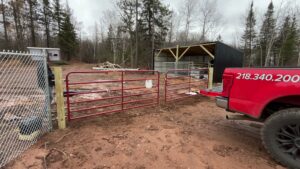 Red metal farm gates and a chain-link fence installed in a rural area by North Shore Fence Company in Centereach, NY.