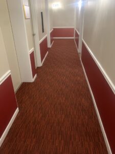 A hallway with newly installed red patterned carpet by Flooring Xpress Enterprise in Chicago, IL.