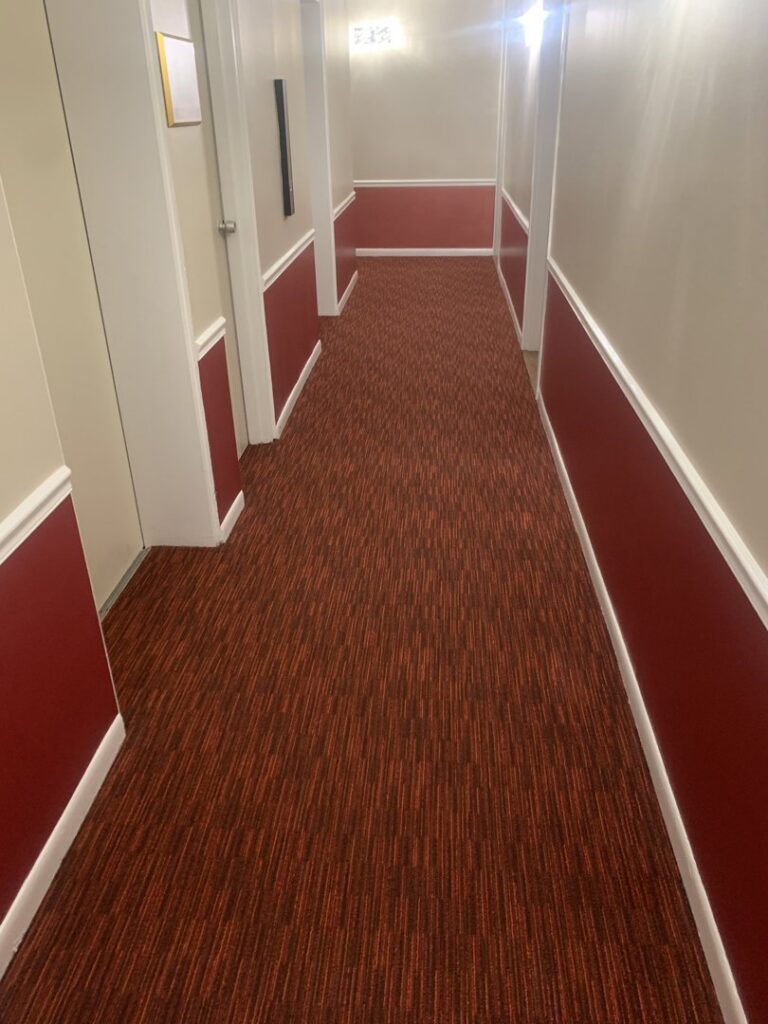 A hallway with newly installed red patterned carpet by Flooring Xpress Enterprise in Chicago, IL.