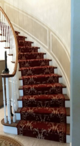 A red patterned carpet runner beautifully installed on a curved wooden staircase by 1 Chicago Carpet Cleaner in Plainfield, IL.