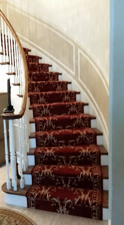 A red patterned carpet runner beautifully installed on a curved wooden staircase by 1 Chicago Carpet Cleaner in Plainfield, IL.