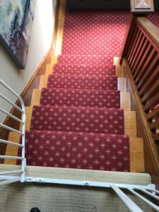 Red patterned carpet with star design beautifully installed on a wooden staircase by Straus Carpets in Oakland, CA.