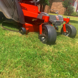 A close-up view of a red riding lawn mower on a freshly cut green lawn by Thorn Lawn Service in Montgomery, AL.