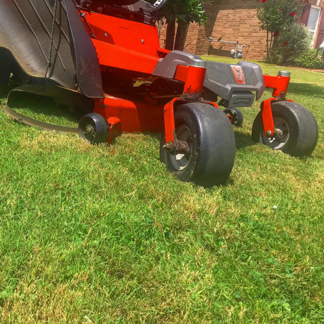A close-up view of a red riding lawn mower on a freshly cut green lawn by Thorn Lawn Service in Montgomery, AL.