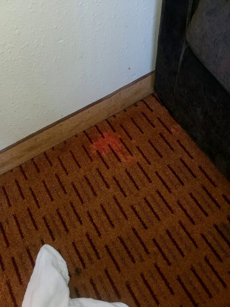 A visible red stain on patterned brown carpet, indicating a need for cleaning or repair by Columbia Flooring Group in Troutdale, OR