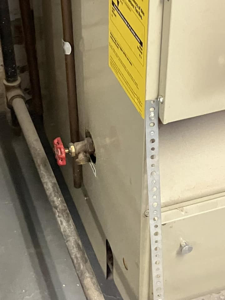 A red-handled valve and copper pipes connected to a furnace or water heater, serviced by AVS Heating and Air Conditioning in Alexandria, VA.