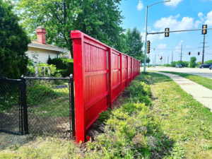 A red wooden privacy fence meeting a black chain-link fence and gate, installed by HammerHorn Fence & Gate Systems in Rochelle, IL.