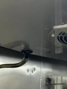 A close-up view of a refrigeration unit component with a pipe and fan, serviced by Kusi.aat' Kaa' Refrigeration in Homer, AK.